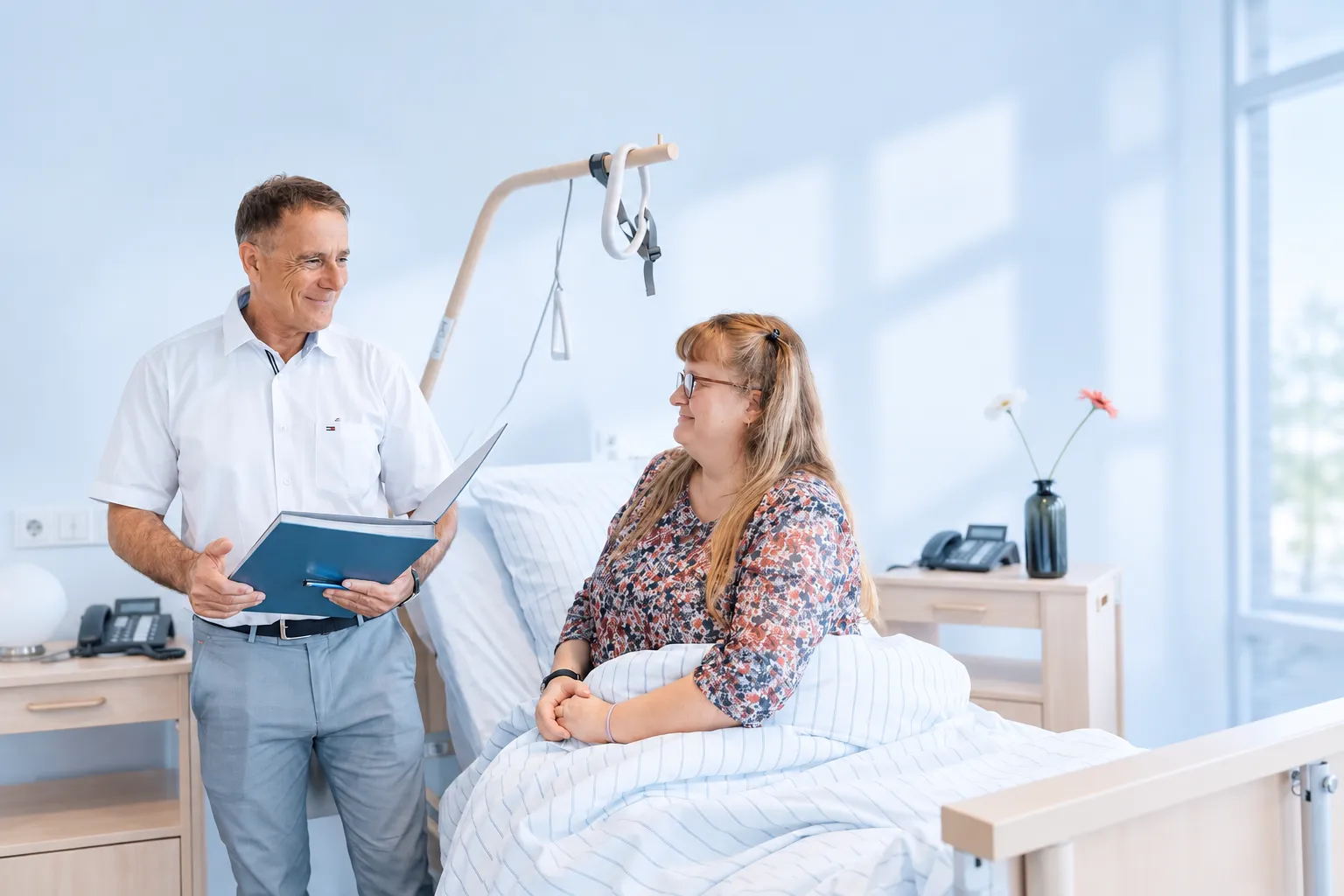 Arzt im Gespräch mit einer Patientin am Krankenbett